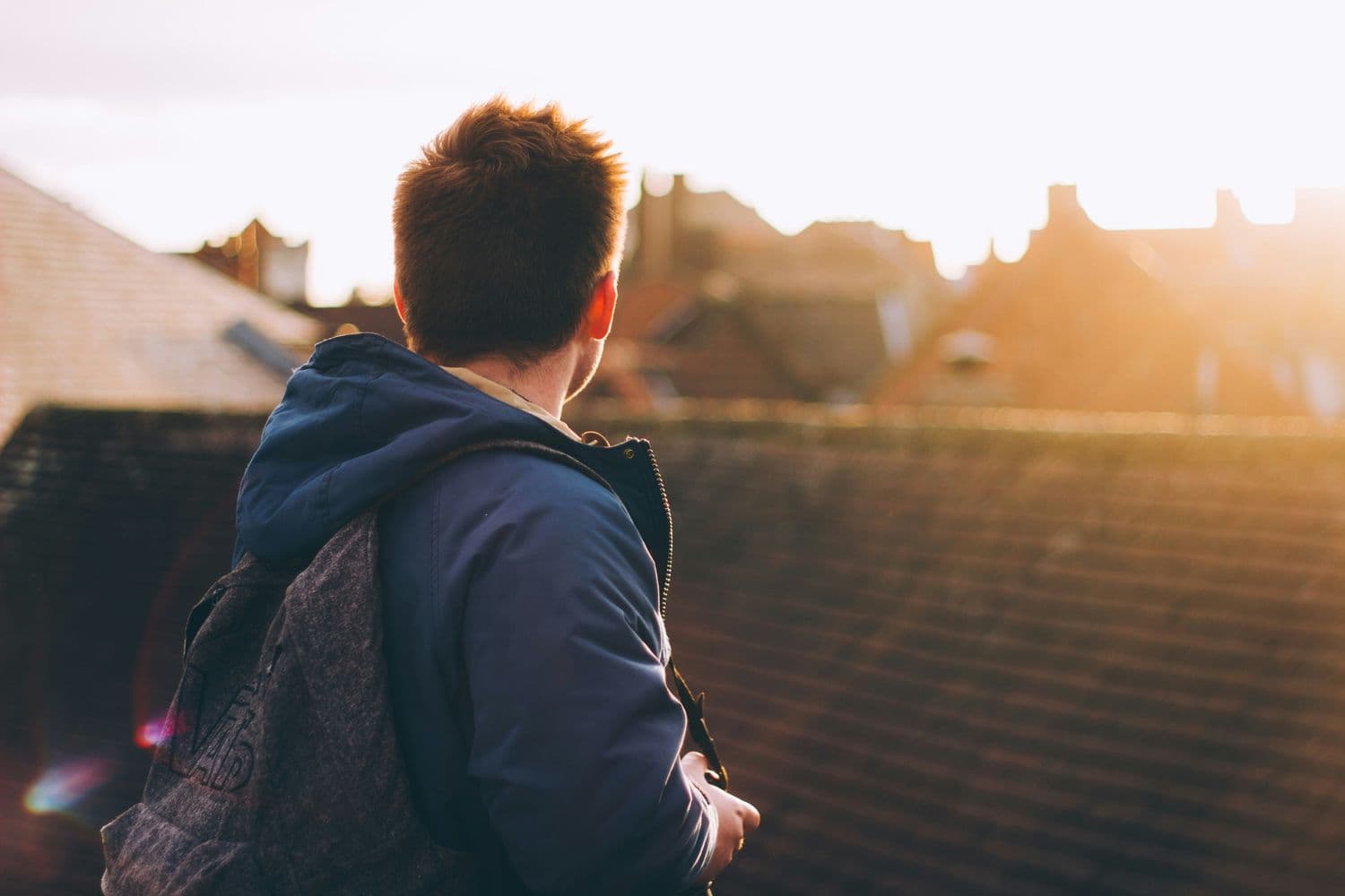 A young person looking out over rooftops at sunset